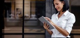 woman using tablet outside of office building