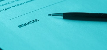 signature line of a document with a pen; blue-green tint