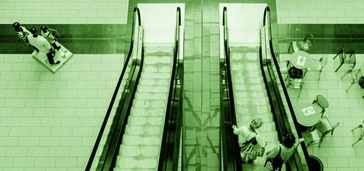 overhead view of people on an escalator, green tint