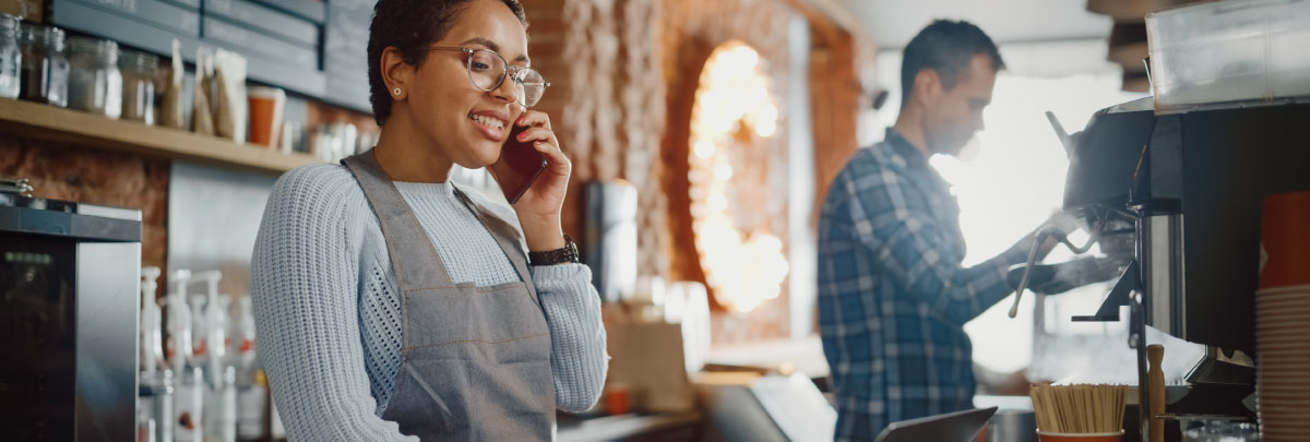 Barista in apron on smartphone